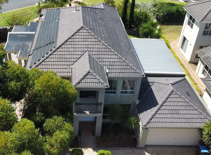 Before: a faded grey tile roof on a two-storey home, seen from above