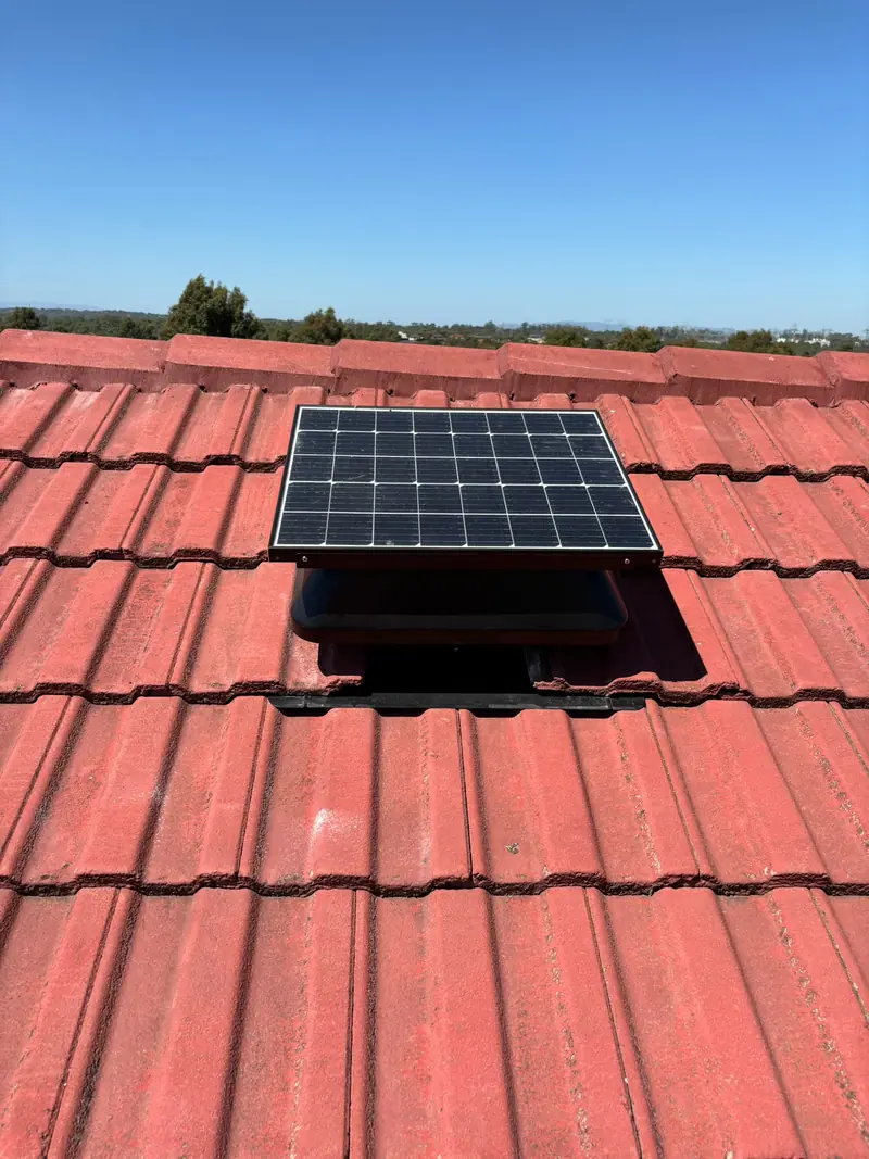 Solar powered roof vent fitted on a red tile roof