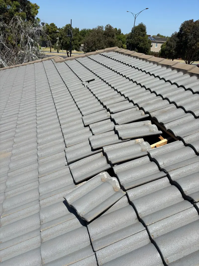 Section of tile roof with broken and displaced tiles exposing the battens